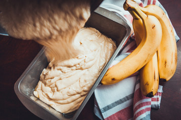 Banana Bread Batter Being Poured From A Mixing Bowl Into A Bread Pan