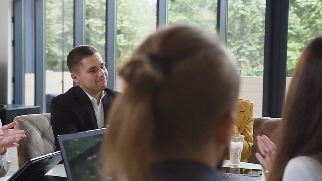 Group of business people applauding congratulating business colleague with successful presentation at conference meeting in light office at park view