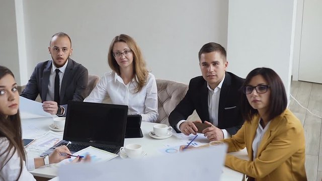 Closeup of young concentrated team of multi ethnic business people conduct analyzing financial documents showing income, charts and graphs, teamwork concept in modern office