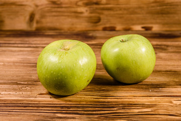 Two ripe green apples on a wooden table
