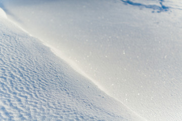 Texture of frosty snow, selective focus on left side of the frame, right side blurred/ frosty winter day, cold snap, frozen lake, little snow dunes due to the wind on the lake, copy space.