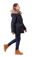 Back view of going woman in jeans and winter jacket.