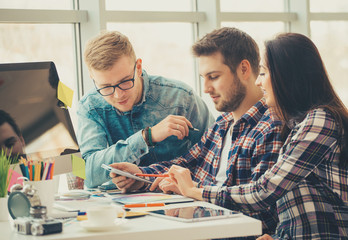 Obraz premium Side view of three creative designer artists working on computer at the office