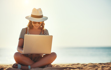 young woman working with laptop on nature in beach.