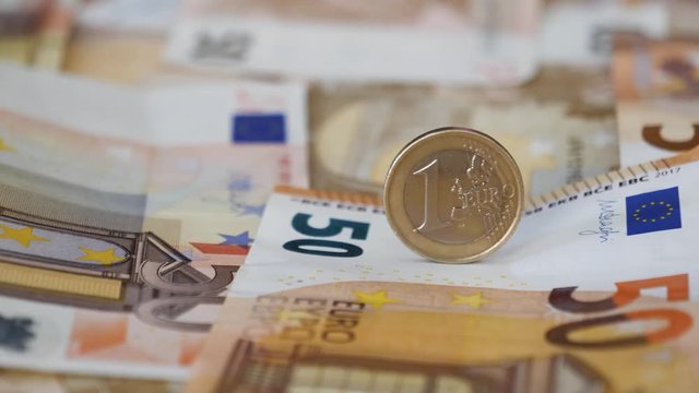 Macro close-up panning across Euro paper and coin currency