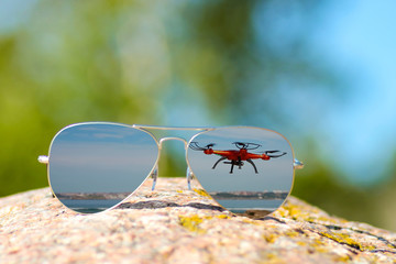 Sunglasses with flying drone and beach reflection