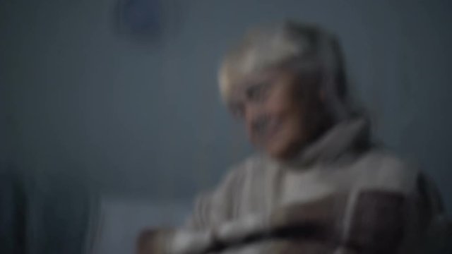 Poor Elderly Woman Sleeping In Chair Behind Rainy Window At Nursing Home