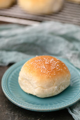 Homemade Dinner Rolls on Cooling Rack with One Isolated on Aqua Plate