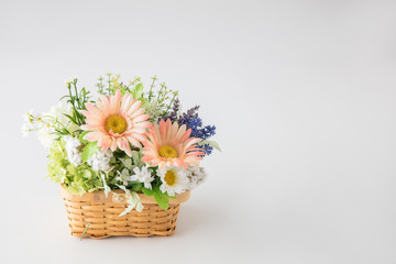 Fototapeta premium 白い背景に花屋に売っていそうなカゴにたくさんの花をつめた花束