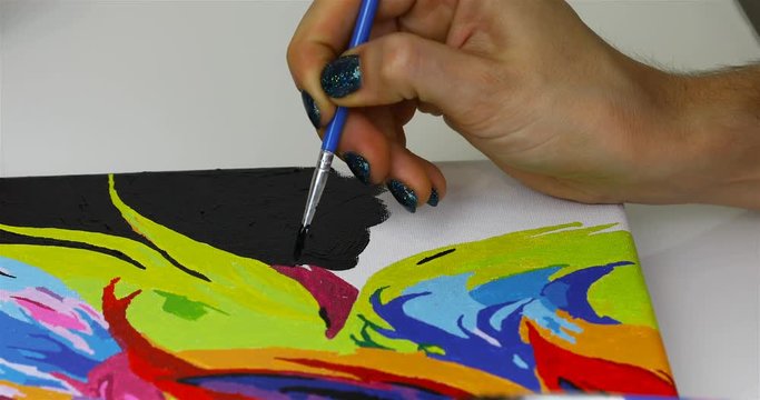 a girl draws a brush with black paint on canvas.