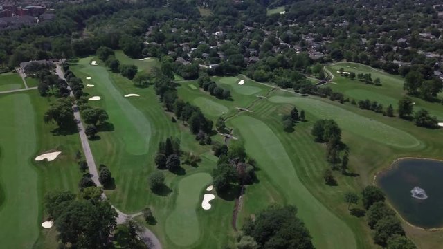 High angle aerial view of golf course, California neighborhood in distance.