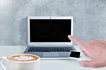 Concept of laptop with black screen on a table, smartphone, a coffee and a hand