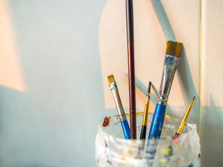 Paint brushes in old plastic cup