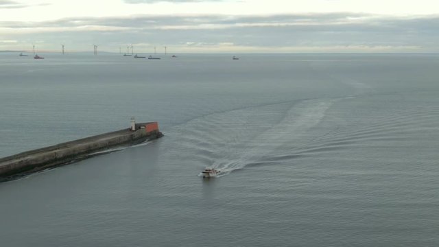 Aerial view of a small boat entering Aberdeen harbour on a cloudy day, Aberdeenshire, Scotland
