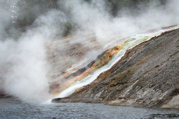 Geyser basin with hot thermal falls running down the colourful rocks at Yellowstone National Park in Wyoming