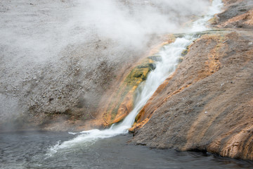 Geyser basin with hot thermal falls running down the colourful rocks at Yellowstone National Park in Wyoming