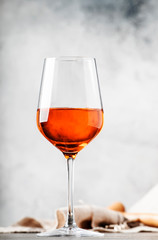 Trendy food and drink, orange wine in glass, gray table background, space for text, selective focus vertical image