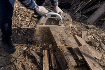 worker cutting wood with circular saw