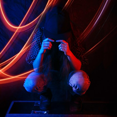 young girl sitting in a cap on a black background in the neon red light lines