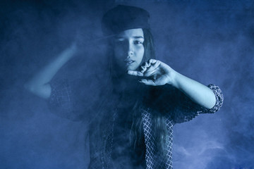 girl in a cap in neon blue light and smoke