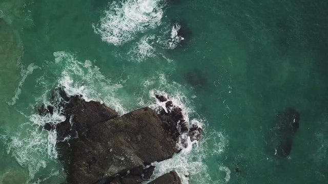 Waves crash against coastal rock formations as camera pans up and rotates