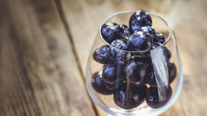 bunch of grapes in a wine glass. on a wooden table.