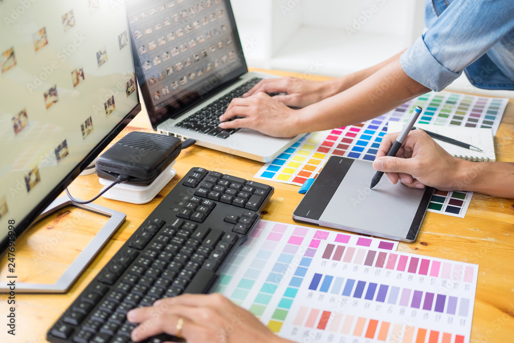 Poster graphic designer team working on web design using color swatches editing artwork using tablet and a 