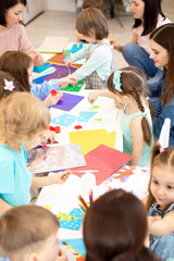 Group of preschool kids working with color paper, sciccors and glue on art class in kindergarten