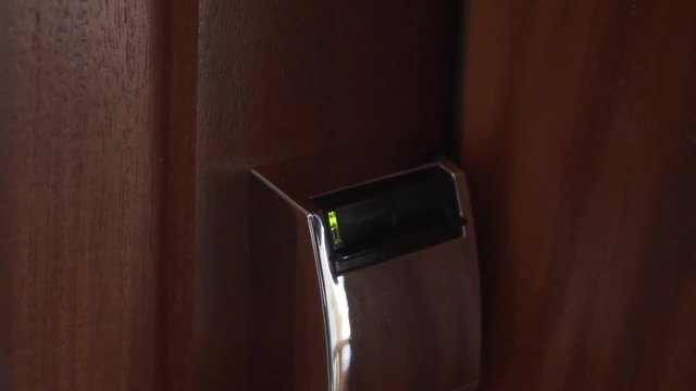 Close up of hotel key card unlocking room door by putting in key card.