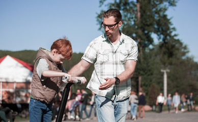 father teaches son to ride a mini-hoverboard in the Park