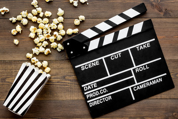 Film watching concept. Clapperboard and popcorn on dark wooden background top view