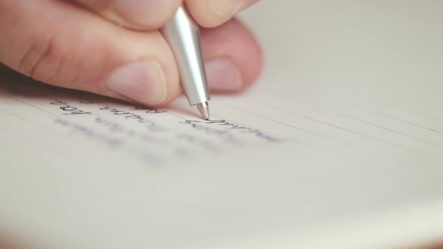 close up a hands writing on the diary book in living room