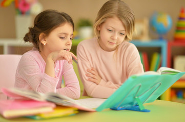 Fototapeta premium Portrait of little girls doing homework together