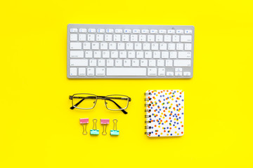 Office desk in order. Geometry. Computer keyboard and office supplies, glasses on yellow background top view