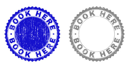 Grunge BOOK HERE stamp seals isolated on a white background. Rosette seals with distress texture in blue and gray colors. Vector rubber overlay of BOOK HERE text inside round rosette.