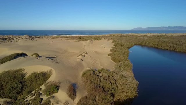 Scenic aerial drone view of tranquil sandy dunes next to a lake in Oso Flaco, located on the Central Coast of California, Santa Barbara County