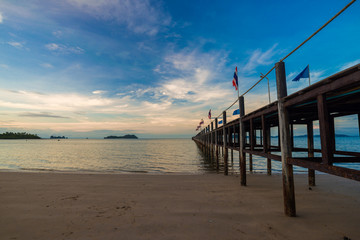 Fototapeta na wymiar Morning sunrise on sea beach with bridge and colorful sky cloud