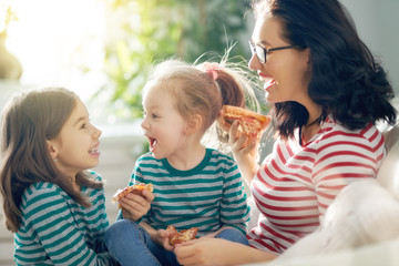 Mother and daughters eating pizza