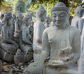 a yard  filled with large marble statues of Buddha