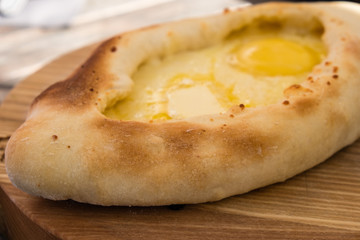 Adjarian khachapuri in restaurant on wooden plate.