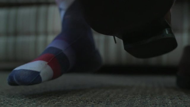 A man puts a brown dress shoe on his foot.