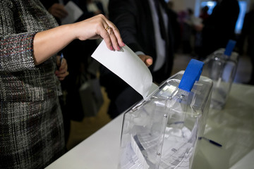 voting at the ballot box. The hand of man putting his vote in the ballot box.