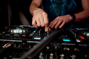 control DJ for mixing music with blurred people dancing at party in nightclub