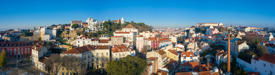 Fototapeta na wymiar Beautiful panoramic Lisbon landmark with tiny houses with moorish architectural elements on the hill; drone view of picturesque labyrinth of narrow streets and small squares in early morning, Portugal