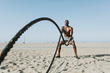 Fototapeta na wymiar Fit man working out with battle ropes