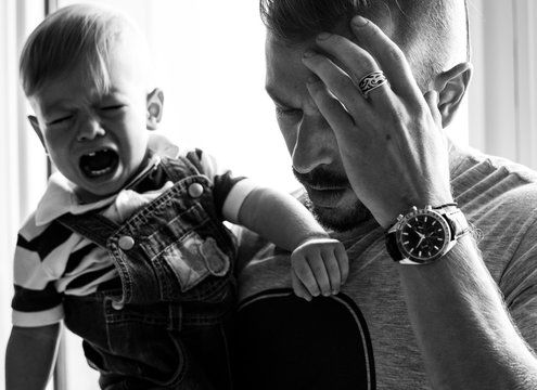 Stressed Out Father Holding A Crying Baby