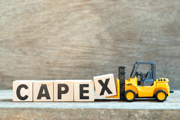Toy forklift hold letter block x to complete word capex (abbreviation of capital expenditures) on wood background - obrazy, fototapety, plakaty