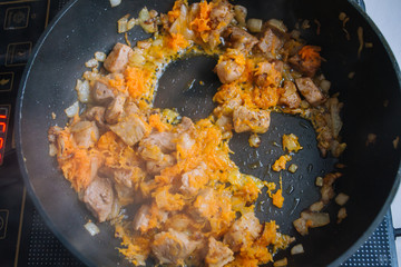 Food preparation. Cooking pork on the pan. Fried pork with onion and carrot. Fresh fried pork prepared at home.
