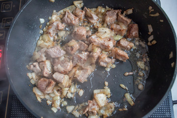 Food preparation. Cooking pork on the pan. Fried pork with onion. Fresh fried pork prepared at home.