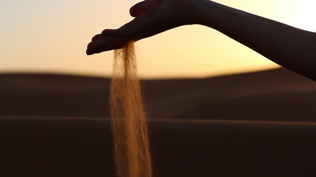Women grabbing fine desert sand during sunset. Desert sand is really fine and not suitable for building purposes. Sand crisis Concept.